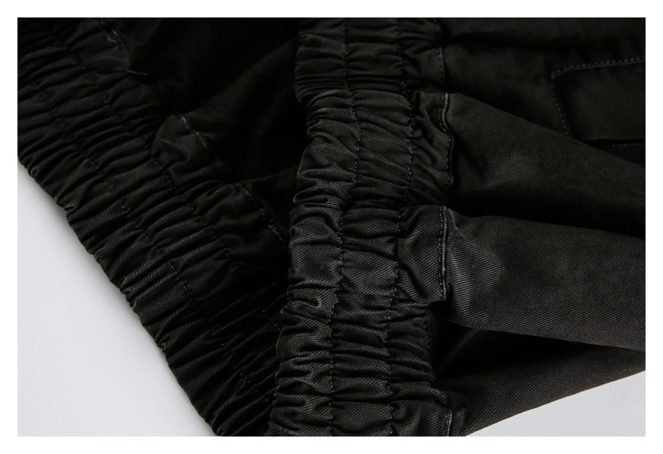 Close-up of the black jacket's gathered elastic hem and stitched construction.