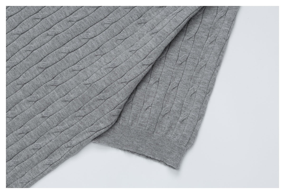 Close-up of the gray cable-knit top showing a sleeve cuff and textured knit panels.