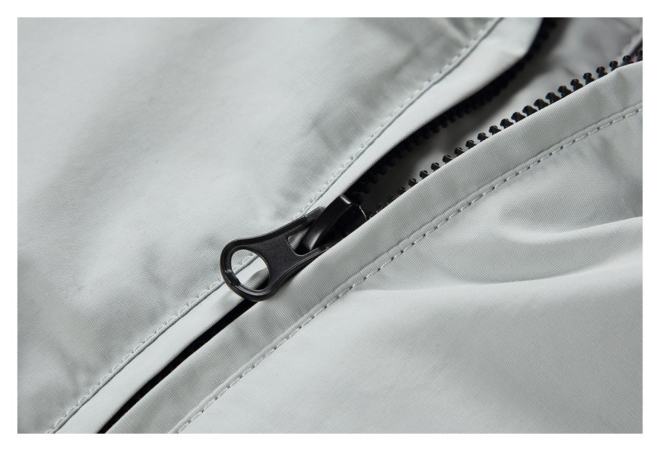 Close-up of a black zipper and stitched seam on light gray garment fabric.