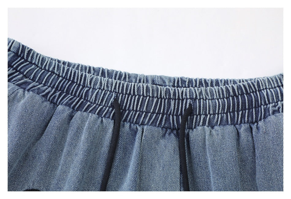 Close-up of blue denim shorts with a gathered elastic waistband and black drawcords.
