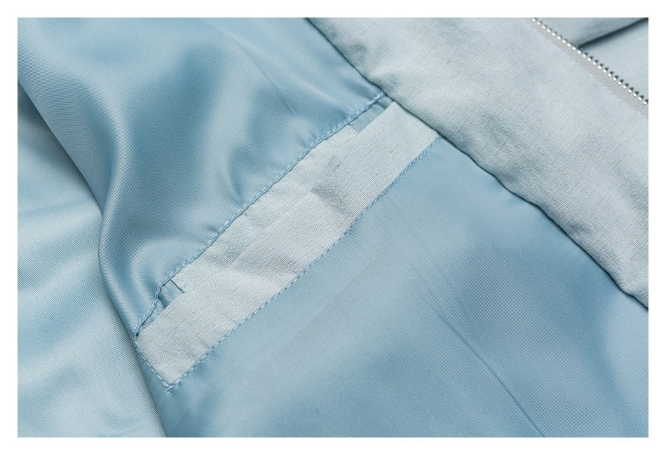 Close-up of pale blue garment fabric, showing a stitched seam and inner panel.
