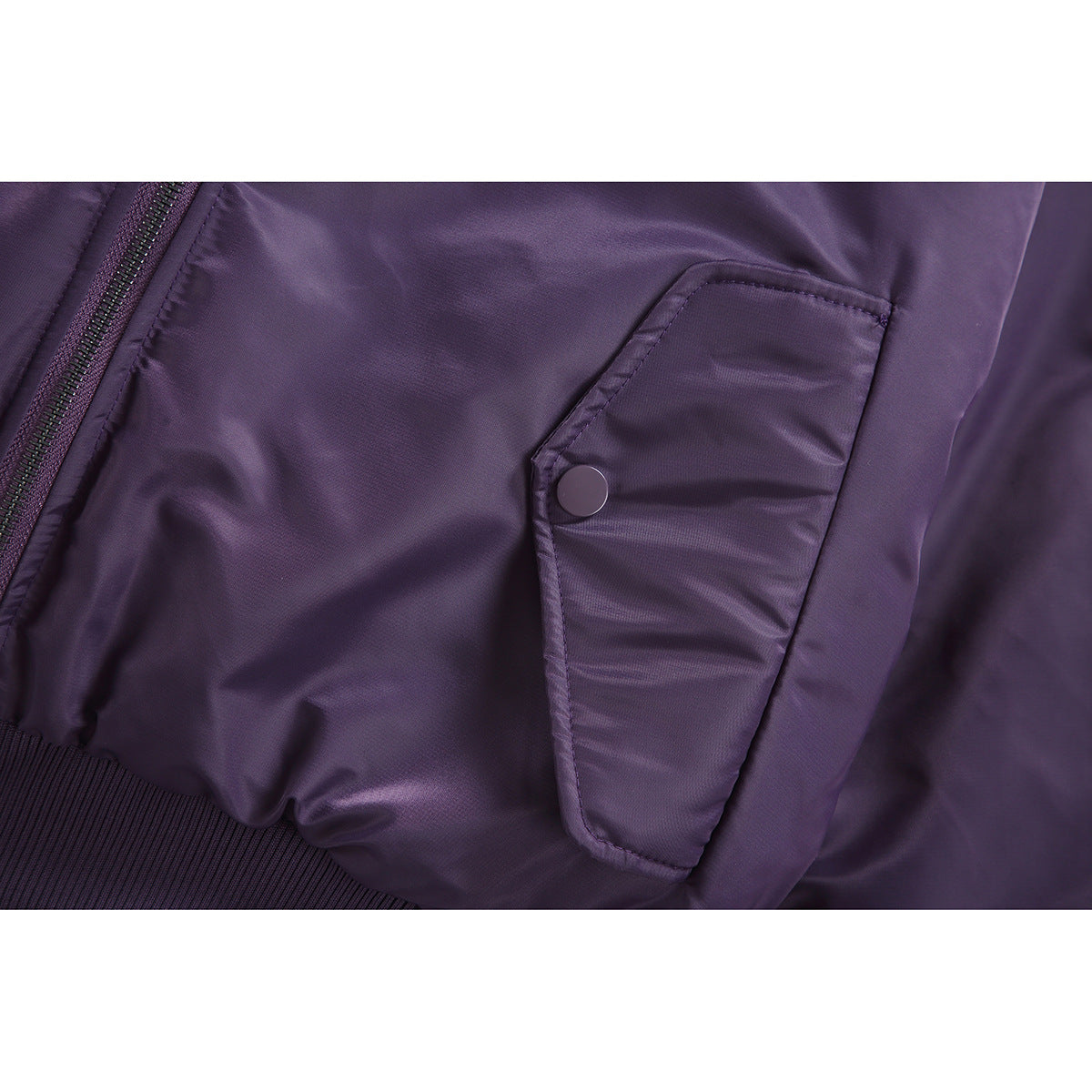 Close-up of a purple bomber jacket's snap-button flap pocket, zipper edge and ribbed hem.
