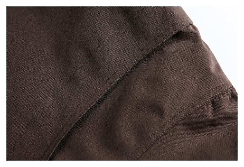 Close-up of brown garment construction with overlapping panels and parallel stitched seams.
