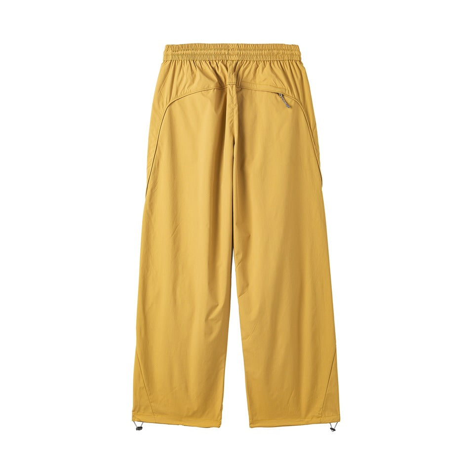 Yellow wide-leg pants back view with elastic waist, curved seams, a zippered pocket and toggle hems