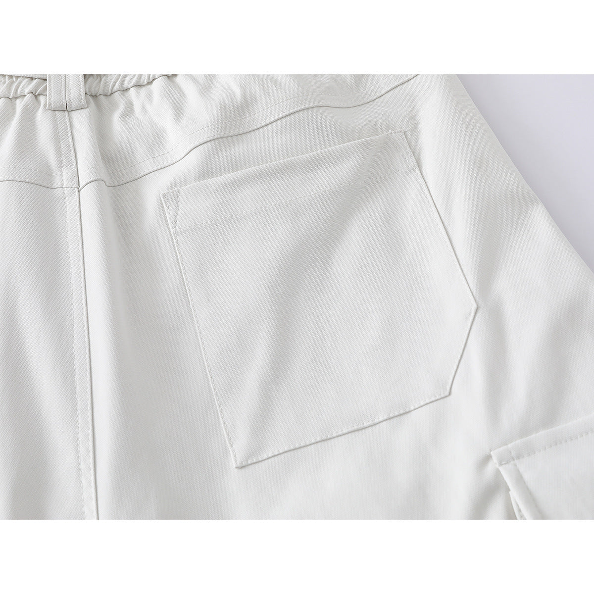 Close-up of the back of ivory shorts, highlighting a large patch pocket and elasticated waistband.