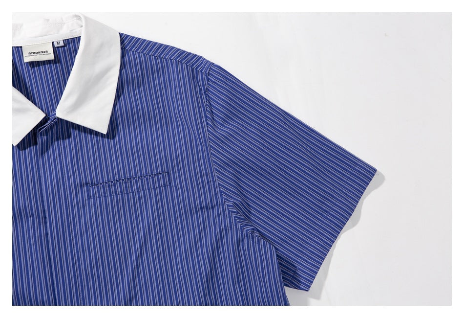 Close view of the short sleeve, shoulder seam, and chest pocket on a blue vertically striped shirt.