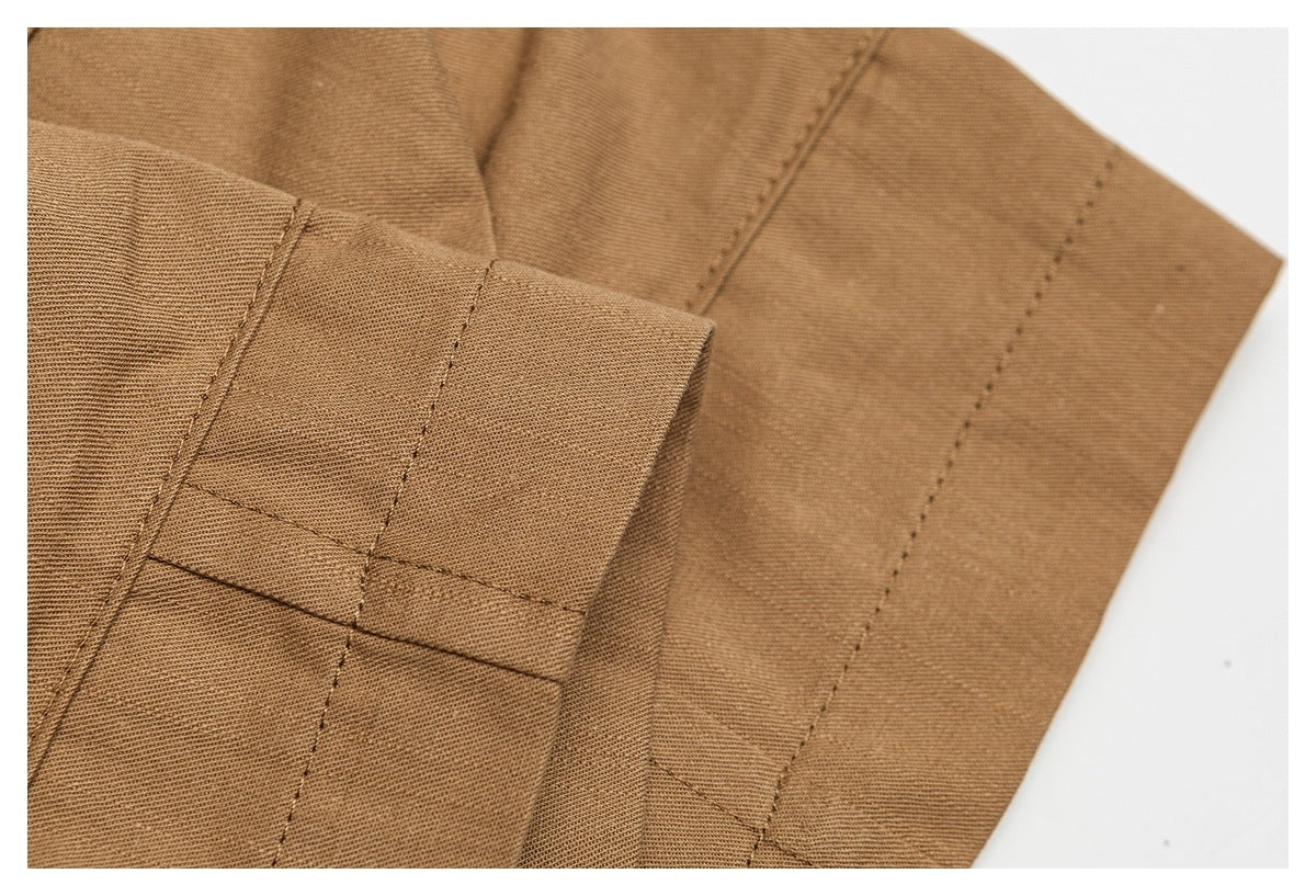 Close-up of tan trouser fabric with folded edges and parallel rows of stitching.