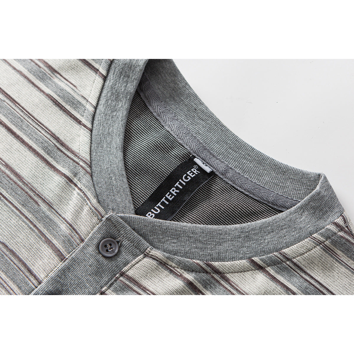 Close-up of a gray ribbed collar, button placket, and sewn brand label on a light striped shirt.