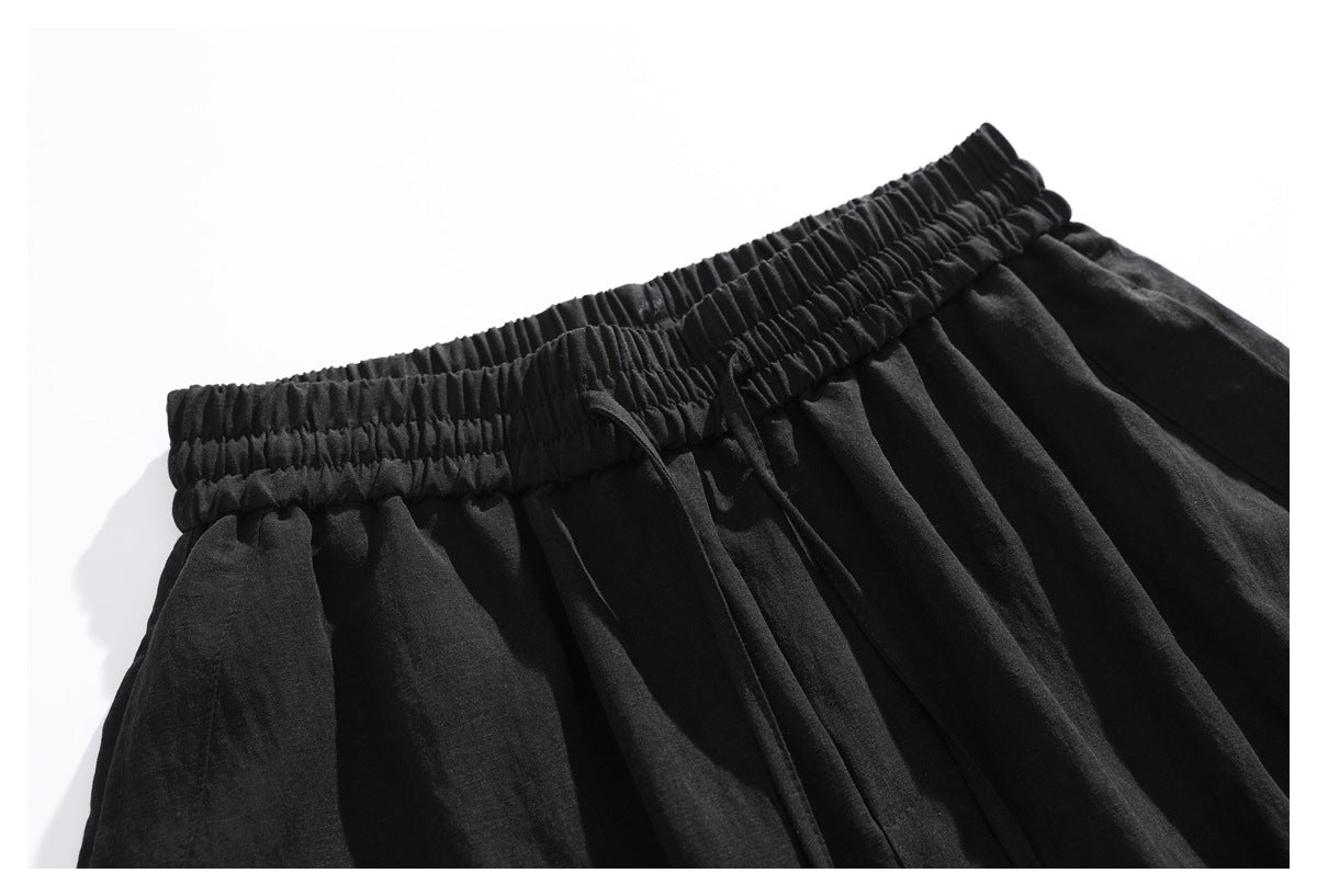 Close-up of black shorts showing the gathered elastic waistband and drawstring.