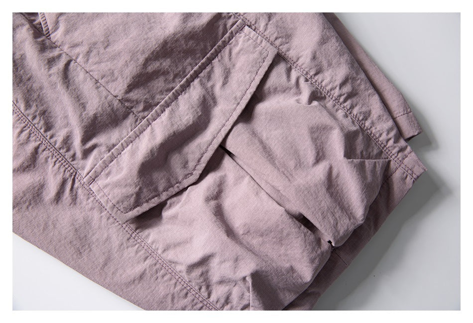 Close-up of dusty mauve garment fabric with stitched seams and a large flap pocket.