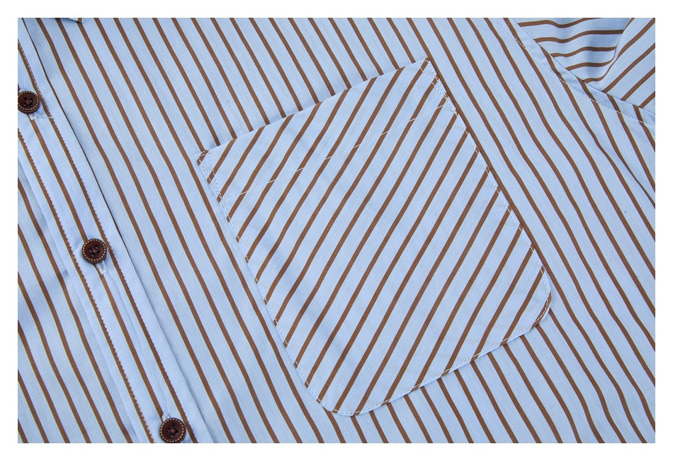 Close-up of the shirt's rounded chest pocket and button placket on light blue fabric with brown stripes.