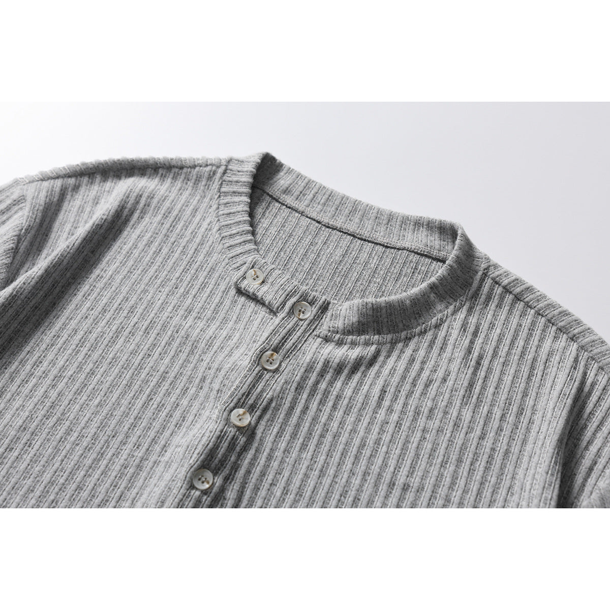 Close-up of a heather gray ribbed henley shirt with a band collar and button placket.