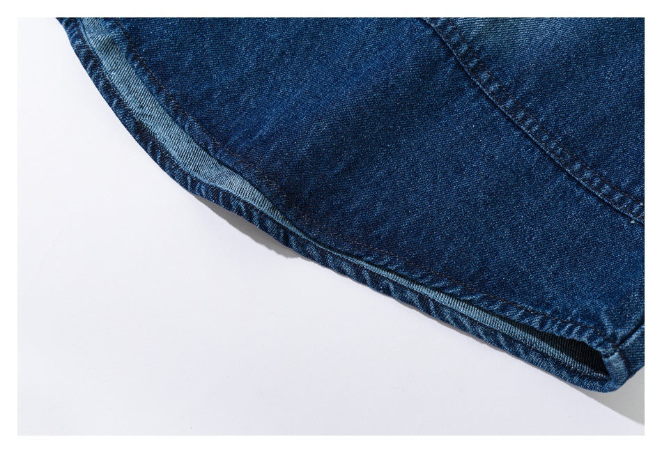 Close-up of the curved stitched hem and edge of a dark blue denim shirt.
