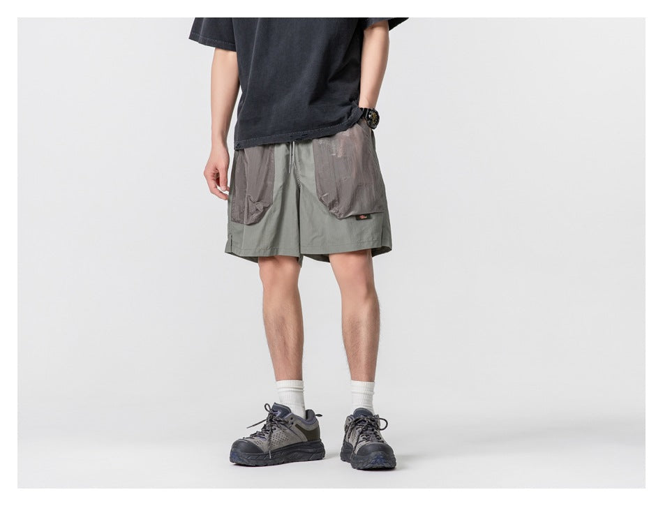Front view of a person wearing sage gray shorts with large contrasting pockets and a drawstring waist.