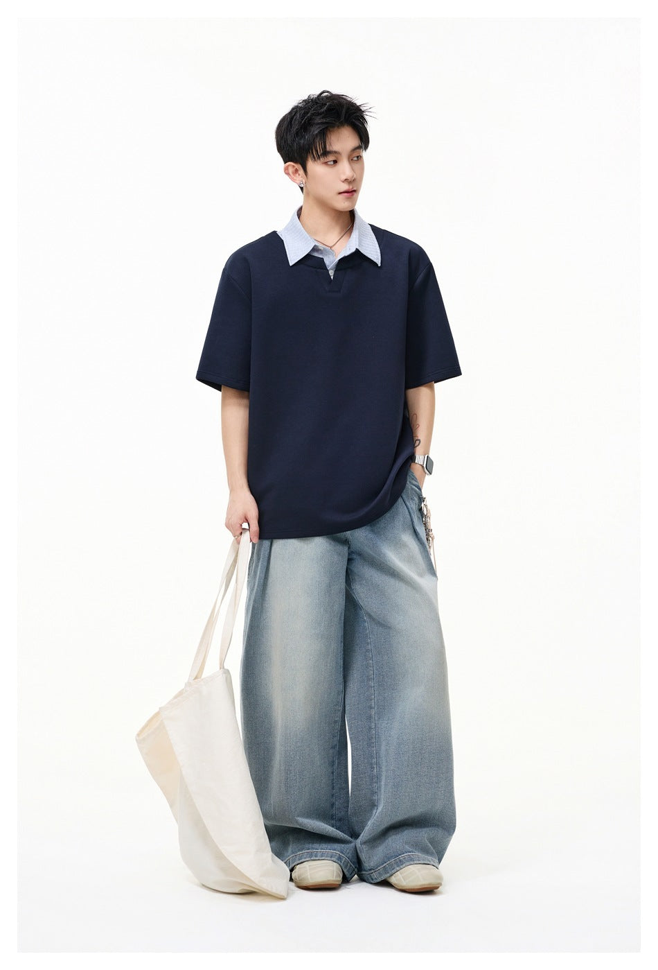 Model wearing a navy short-sleeve top with a striped layered collar, wide-leg jeans and carrying a canvas tote