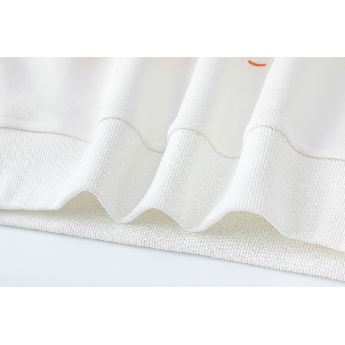 Close-up of a white garment's wide ribbed hem and stitched seam.