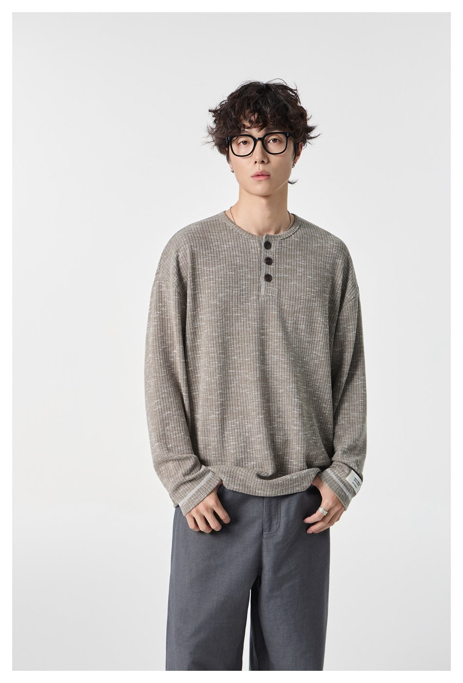 Model wearing a taupe-gray ribbed Henley with a three-button placket and gray trousers.