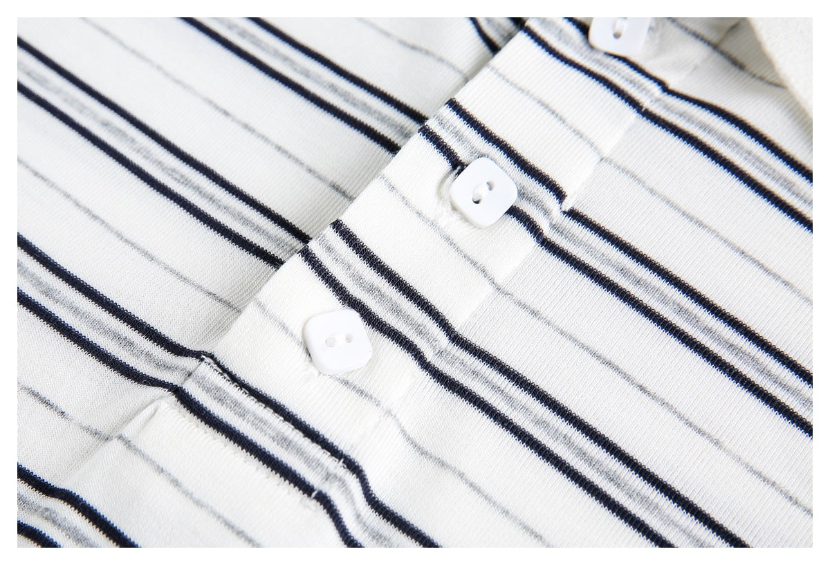 Close-up of two white buttons on the black and gray striped placket of a white polo shirt.