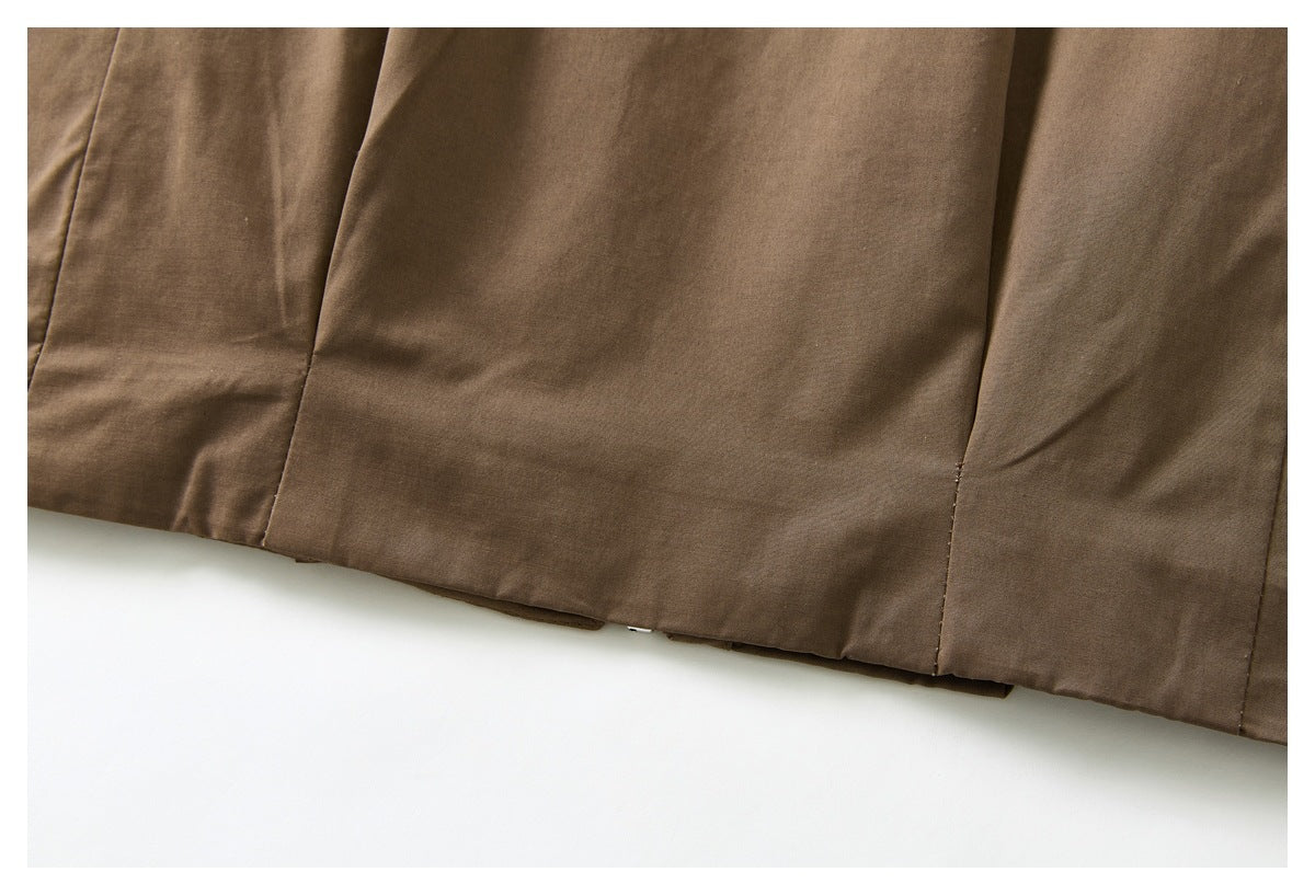 Close-up of a brown garment hem with vertical panel seams against a white background.