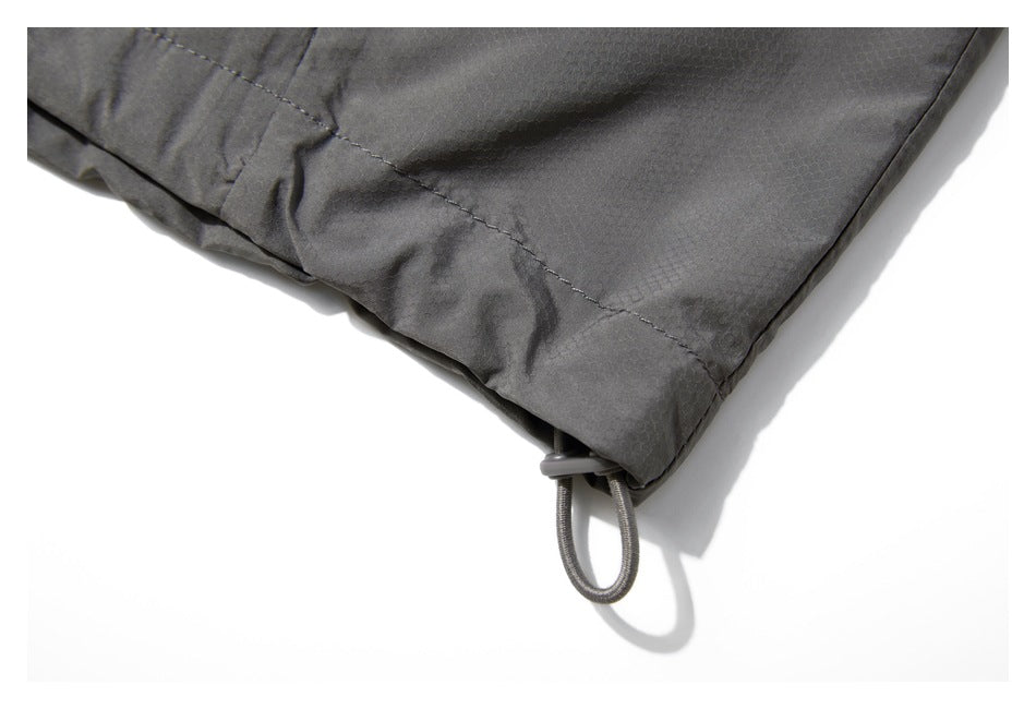 Close-up of a dark gray garment hem with a looped drawcord and adjustment toggle.