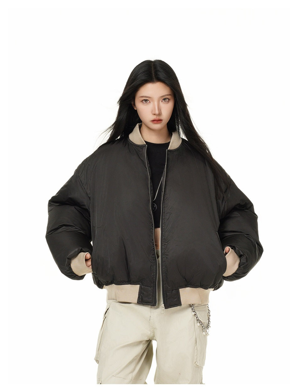 Model wearing a black oversized bomber jacket with beige ribbed collar, cuffs and hem, shown from the waist up.