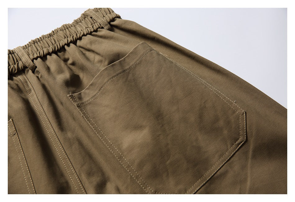 Close-up of a stitched patch pocket on the back of khaki trousers beneath an elastic waistband.