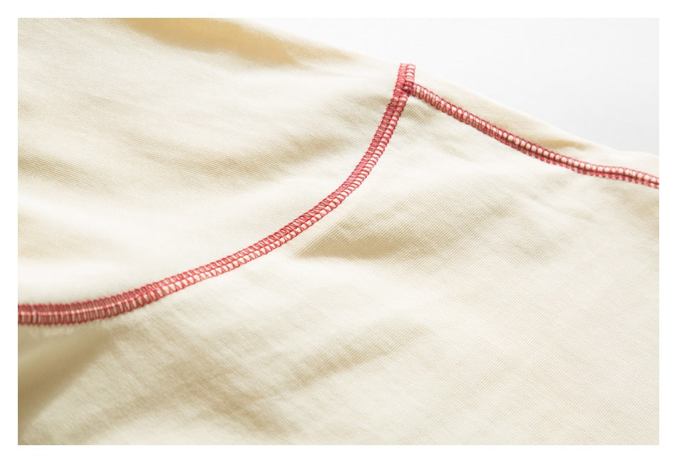 Close-up of cream garment seams finished with red overlock stitching.