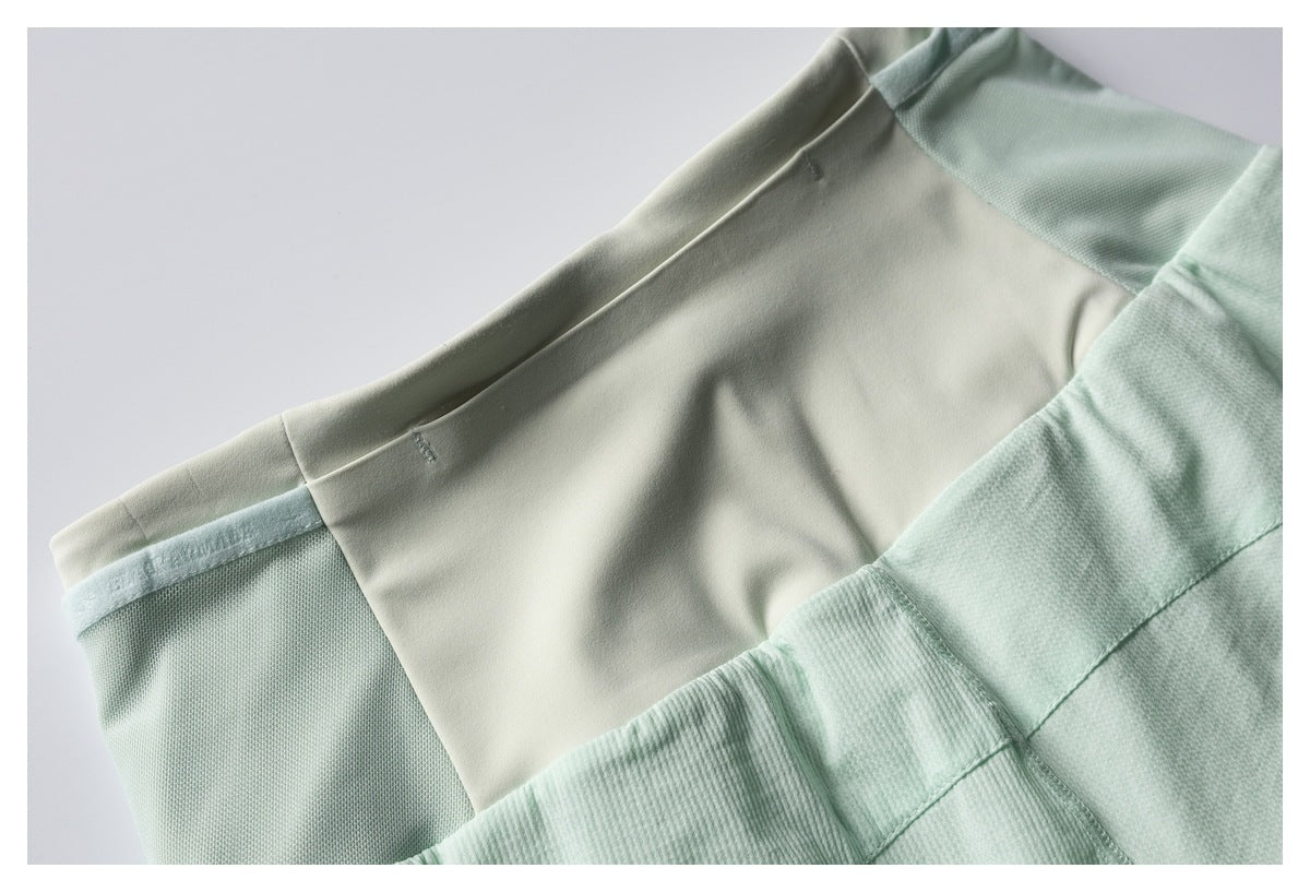 Close-up of mint green shorts showing the pale waistband, smooth upper panel, and textured fabric panels.