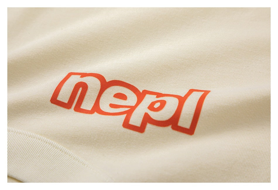 Close-up of red outlined lettering printed on cream T-shirt fabric near a seam.