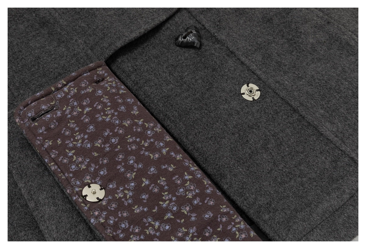 Close-up of a dark charcoal coat showing floral-patterned lining and metal snap fasteners.