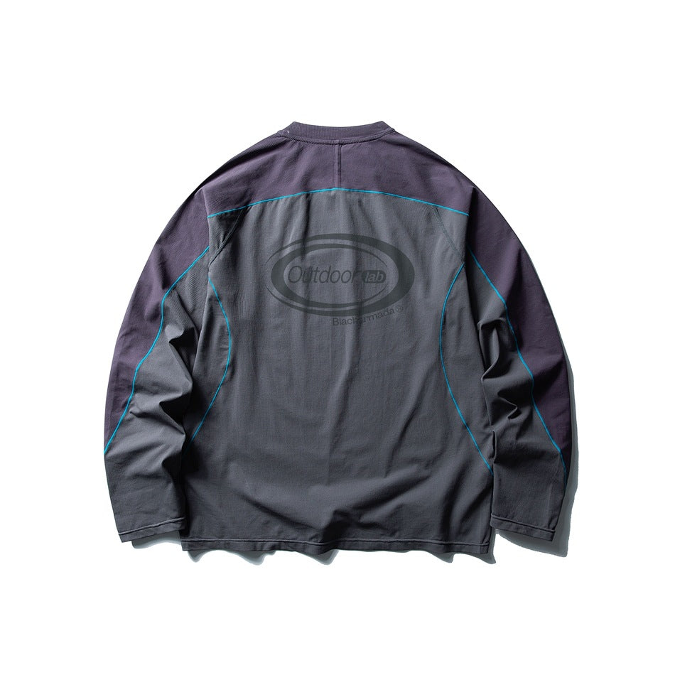 Back view of a charcoal long-sleeve top with purple sleeves, teal piping, and a large oval graphic on the back.