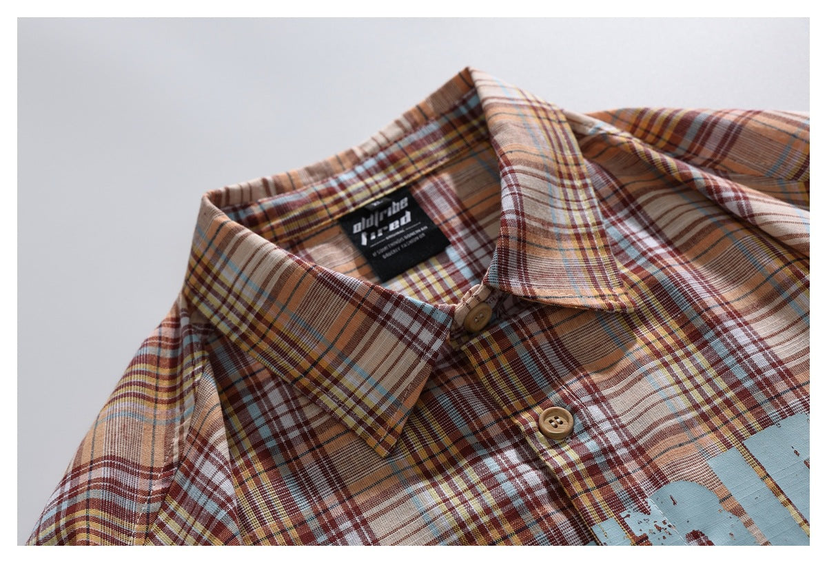 Close-up of a multicolor plaid shirt collar and upper placket with tan buttons and a sewn neck label.