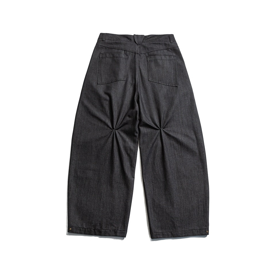 Back view of dark charcoal wide-leg trousers laid flat, showing two rear pockets and ankle rivets.