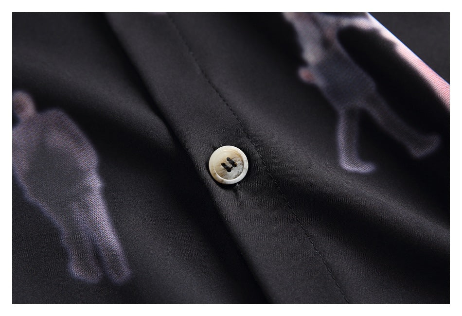 Close-up of a light-colored button on the black shirt's printed fabric.