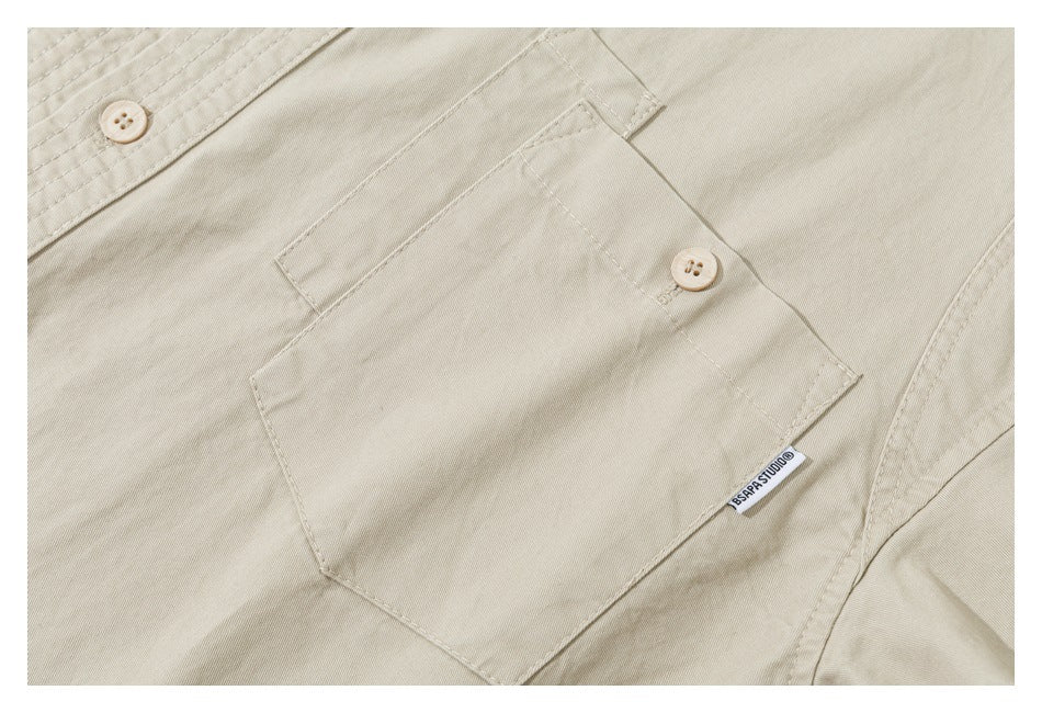 Close-up of a beige garment pocket with a buttoned flap and small woven label.