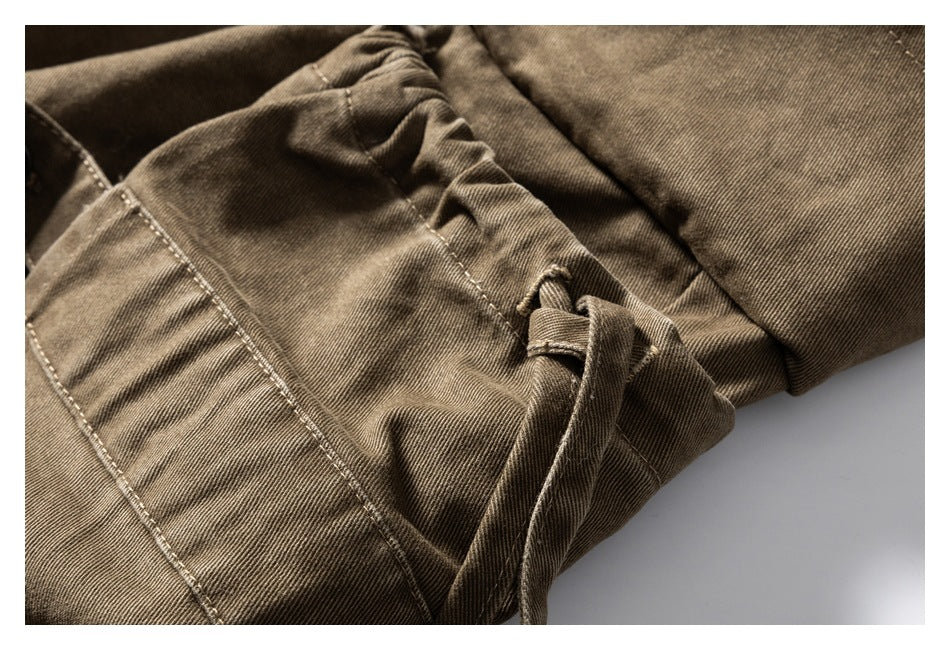 Close-up of gathered khaki-brown fabric with a stitched seam and narrow drawcord.