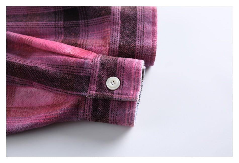 Close-up of a buttoned cuff on a pink and dark plaid shirt.