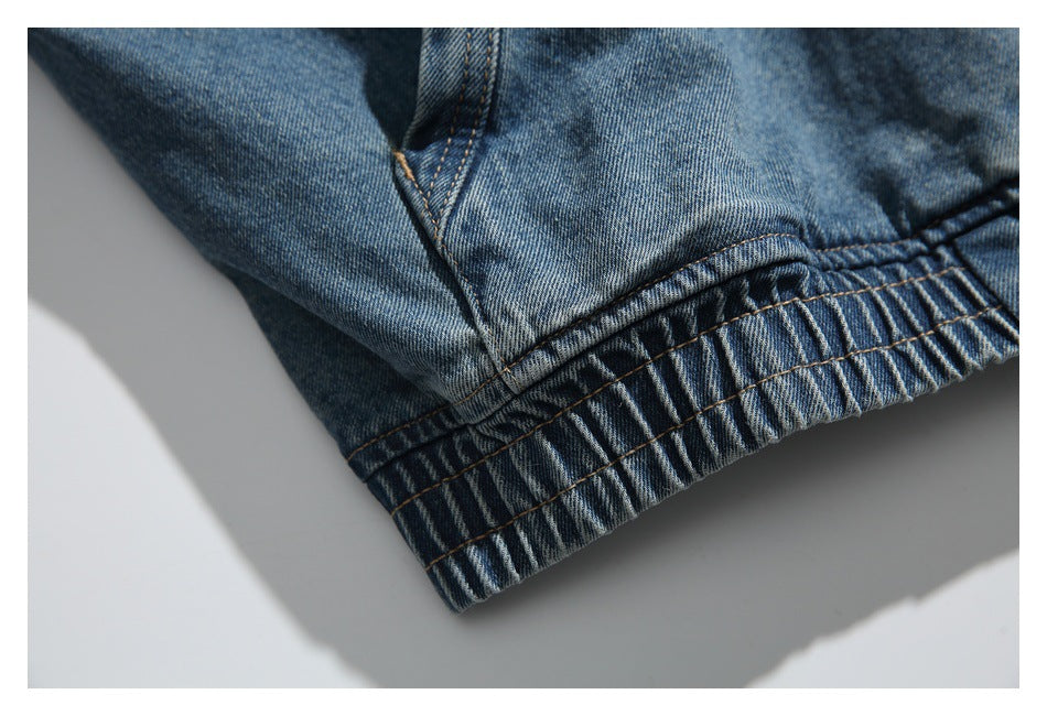 Close-up of the denim hoodie's gathered elastic hem and parallel stitching.