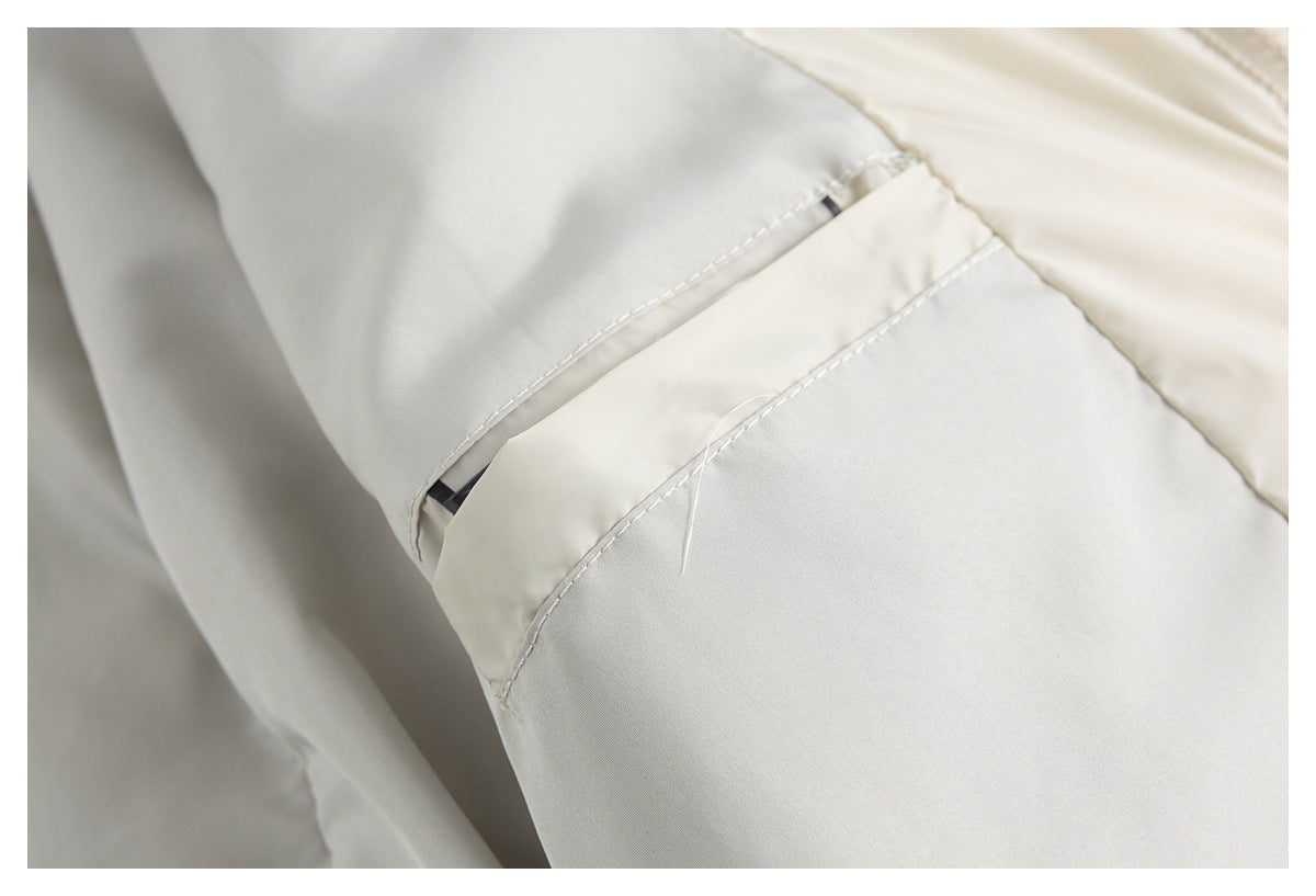 Close-up of an ivory jacket seam and narrow pocket opening.
