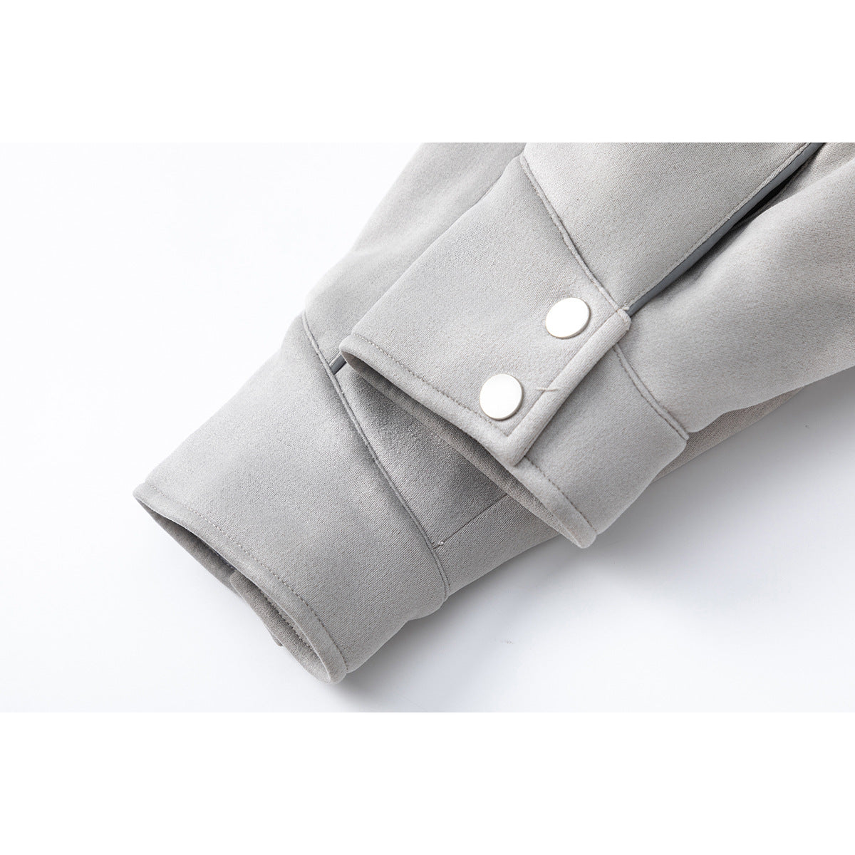 Close-up of a light gray coat sleeve cuff with a two-snap adjustment tab and dark piping.
