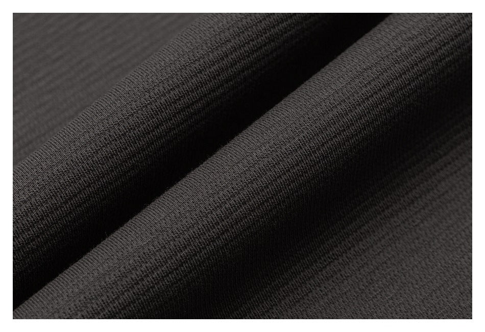 Macro view of the dark charcoal garment fabric folded into ridges.