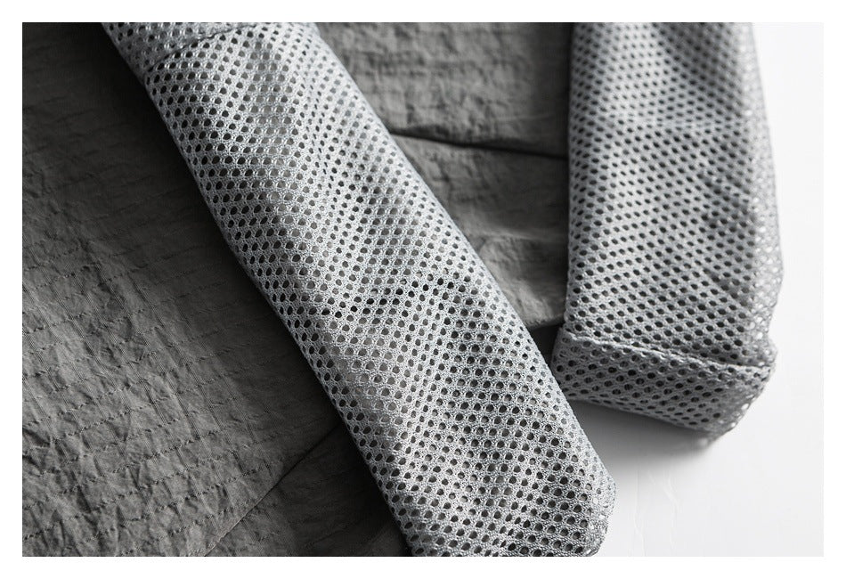 Close-up of the garment's gray perforated mesh lining beside the charcoal outer fabric.
