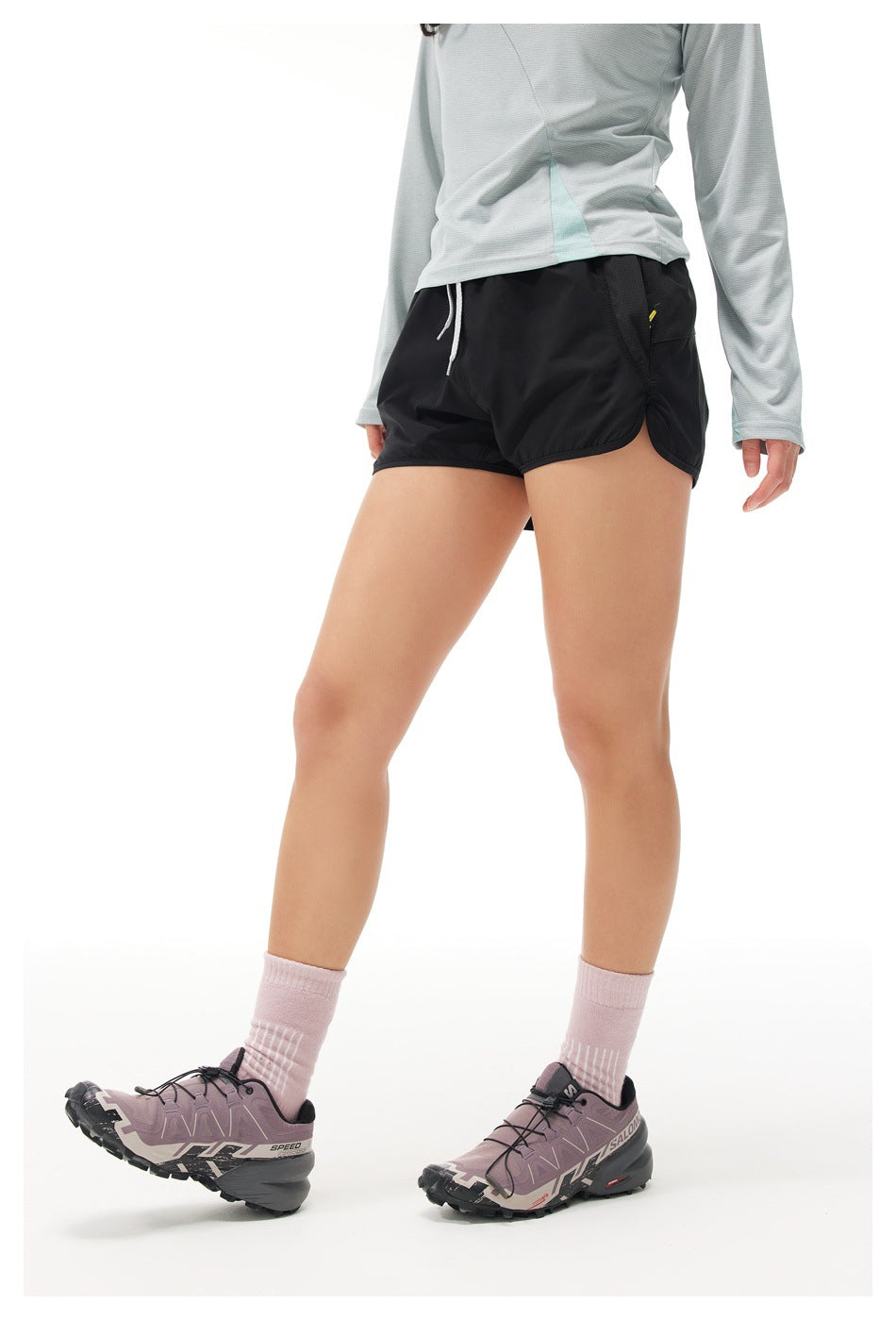 Angled view of a model wearing black running shorts with side pockets and curved hems.
