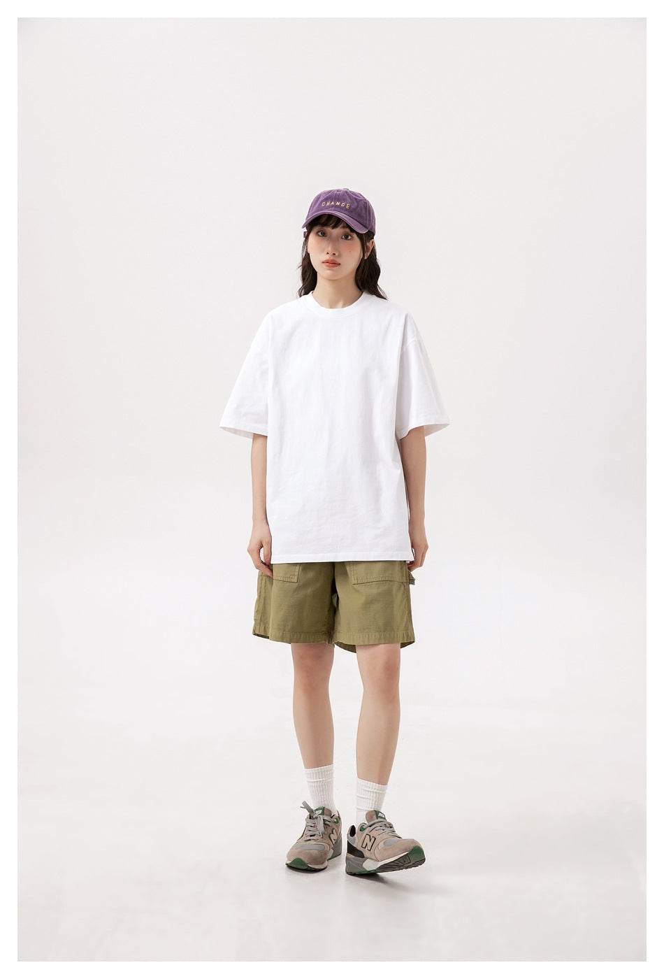 Full-length front view of a model wearing an oversized plain white T-shirt and olive cargo shorts.