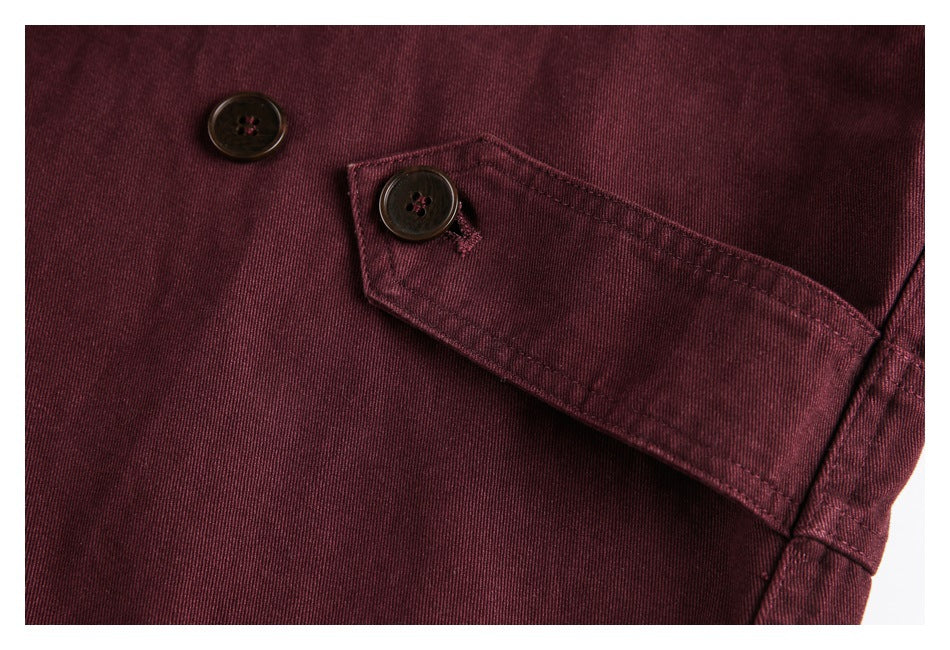 Close-up of burgundy garment with a buttoned flap pocket and visible stitching.