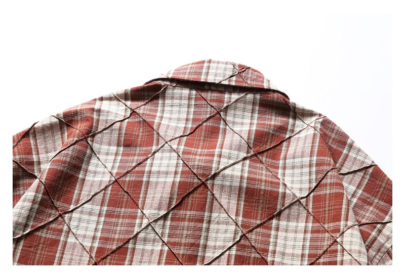 Close-up of the back and collar of a reddish-brown, cream, and gray plaid shirt with diamond-shaped stitched detailing.