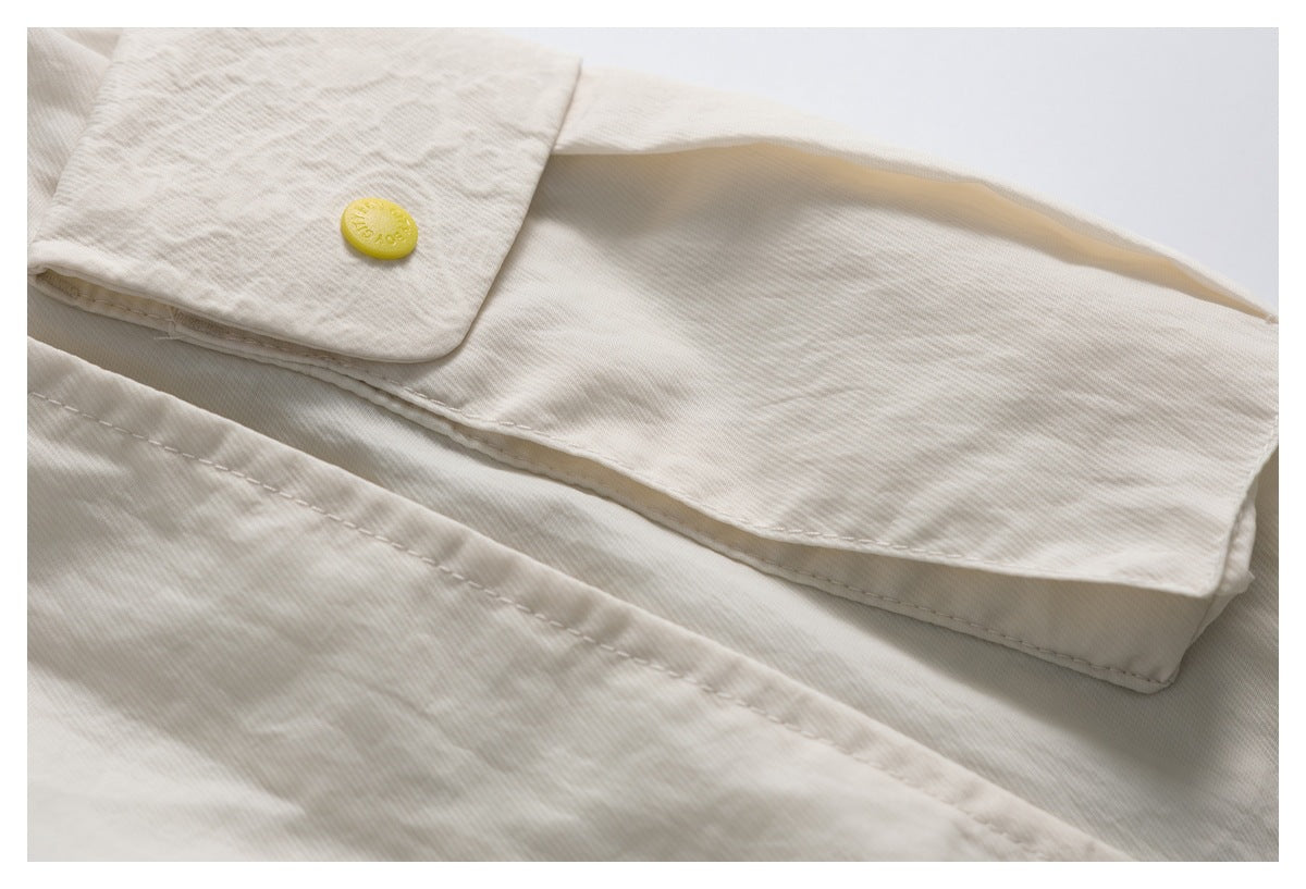 Close-up of a cream garment flap with a small round yellow button and visible stitching.