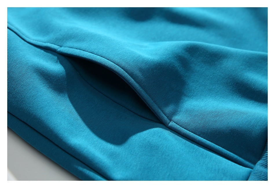 Close-up of a stitched pocket opening on the teal garment.