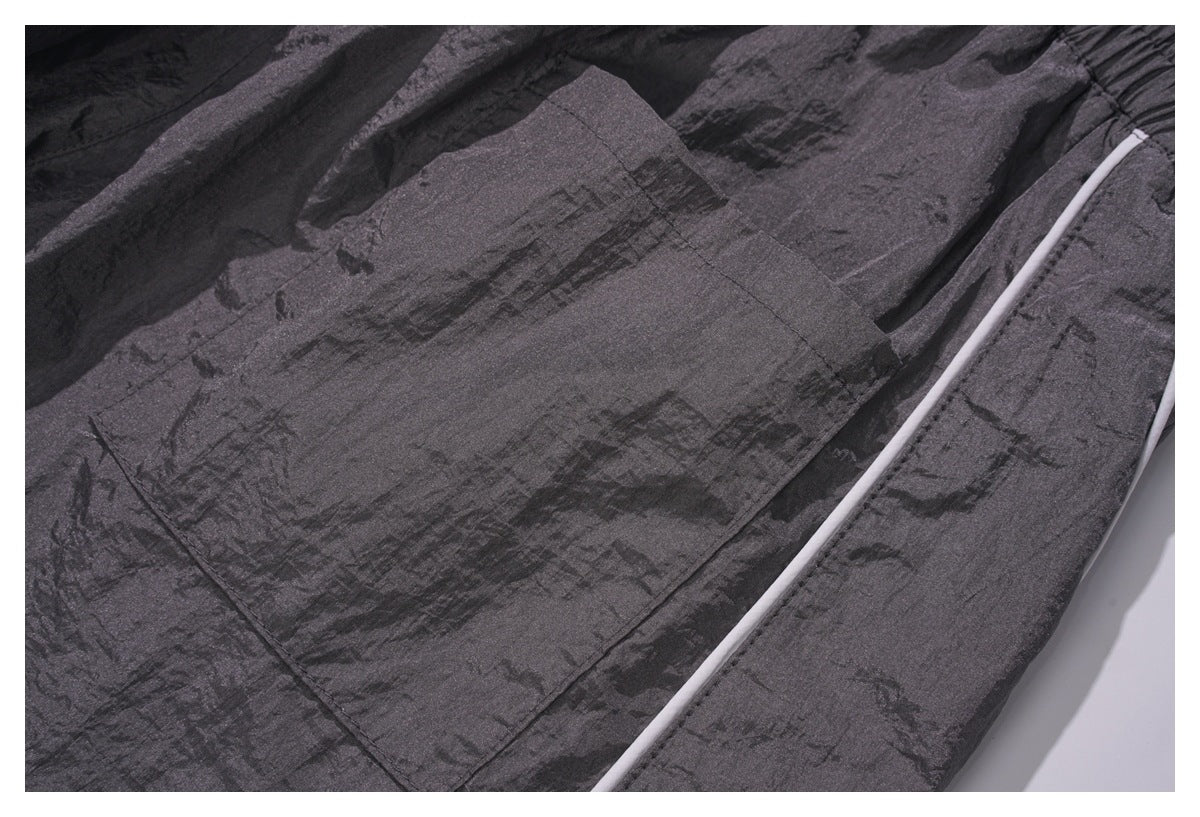 Close-up of a large patch pocket and white piping on dark charcoal fabric.
