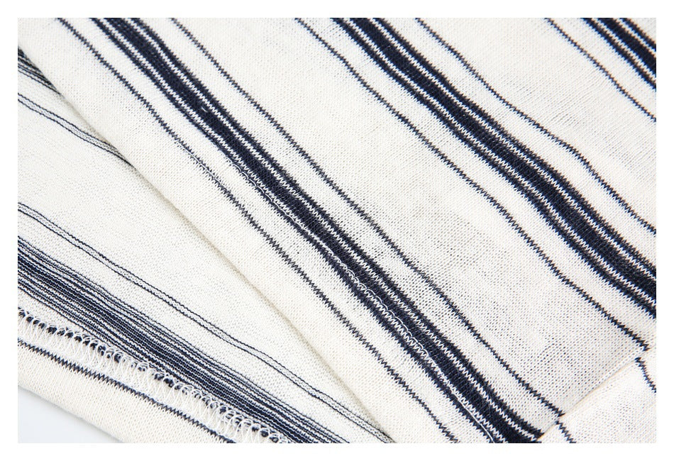 Close-up of the striped garment's stitched edge and seam on ivory fabric.
